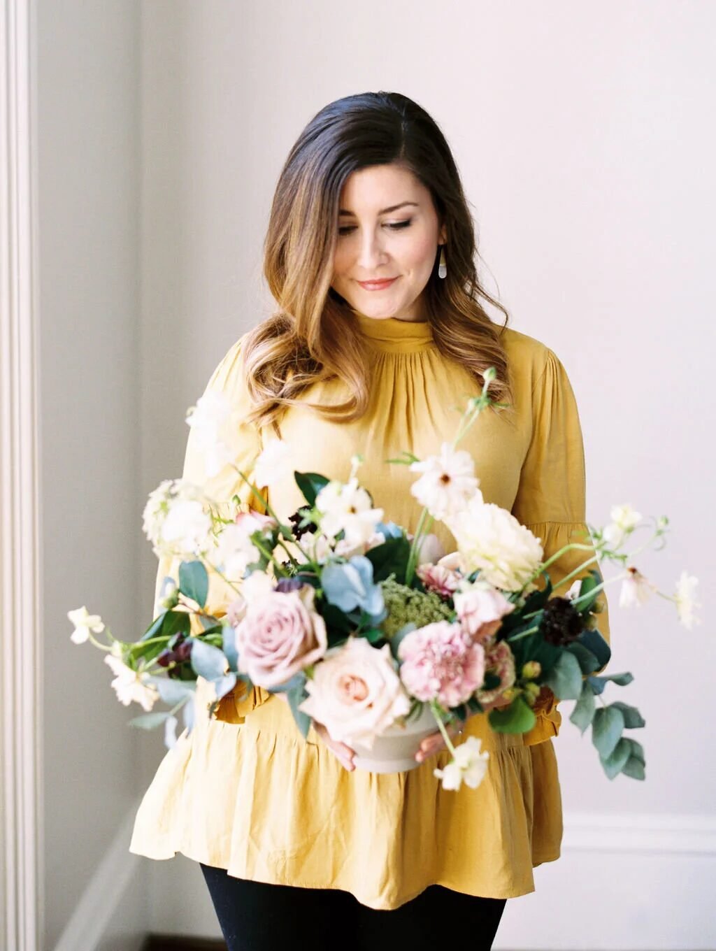Andraya, founder of FLORA, holding a lush garden-style arrangement
